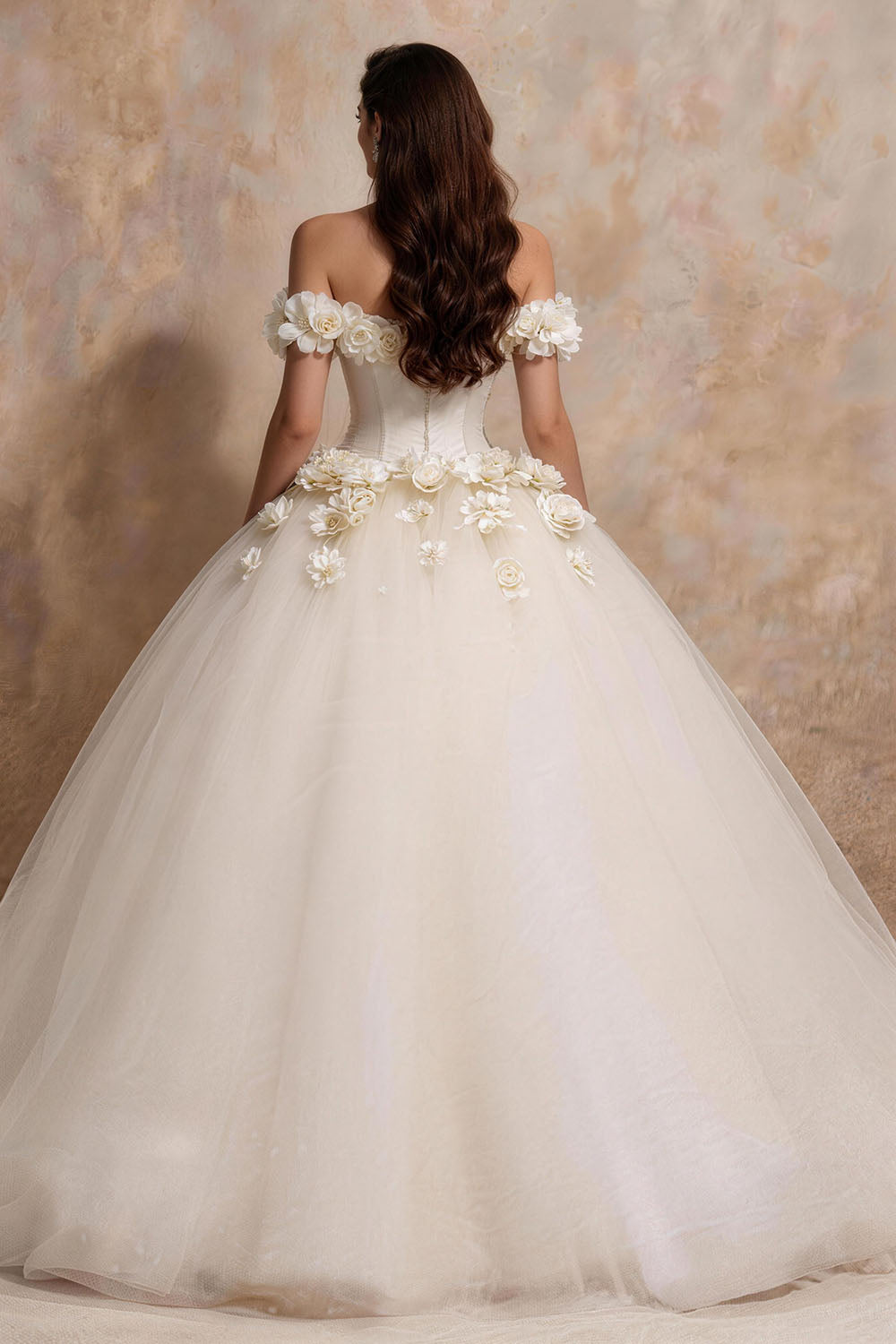 White fitted tulle wedding gown featuring ruching, floral details, and a voluminous skirt.